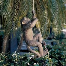 Statue décorative en résine d'un bébé chimpanzé grimpant sur un arbre dans un décor de jardin animal