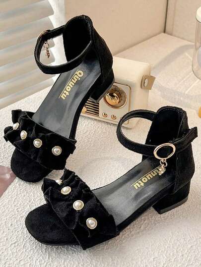 2025新款女童小跟凉鞋。黑色绒面革鞋面。荷叶边蝴蝶结珍珠装饰。踝带设计。低跟，优雅甜美风格。适合3-12岁女孩搭配连衣裙出席正式场合或日常穿着，展现她们的公主气质。