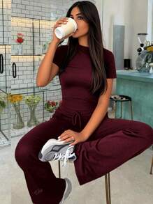Tuta sportiva da donna alla moda per la primavera, con top a maniche corte che scopre la pancia e pantaloni a zampa aderenti con lacci