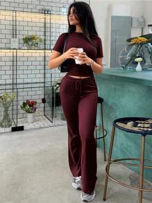 Tuta sportiva da donna alla moda per la primavera, con top a maniche corte che scopre la pancia e pantaloni a zampa aderenti con lacci