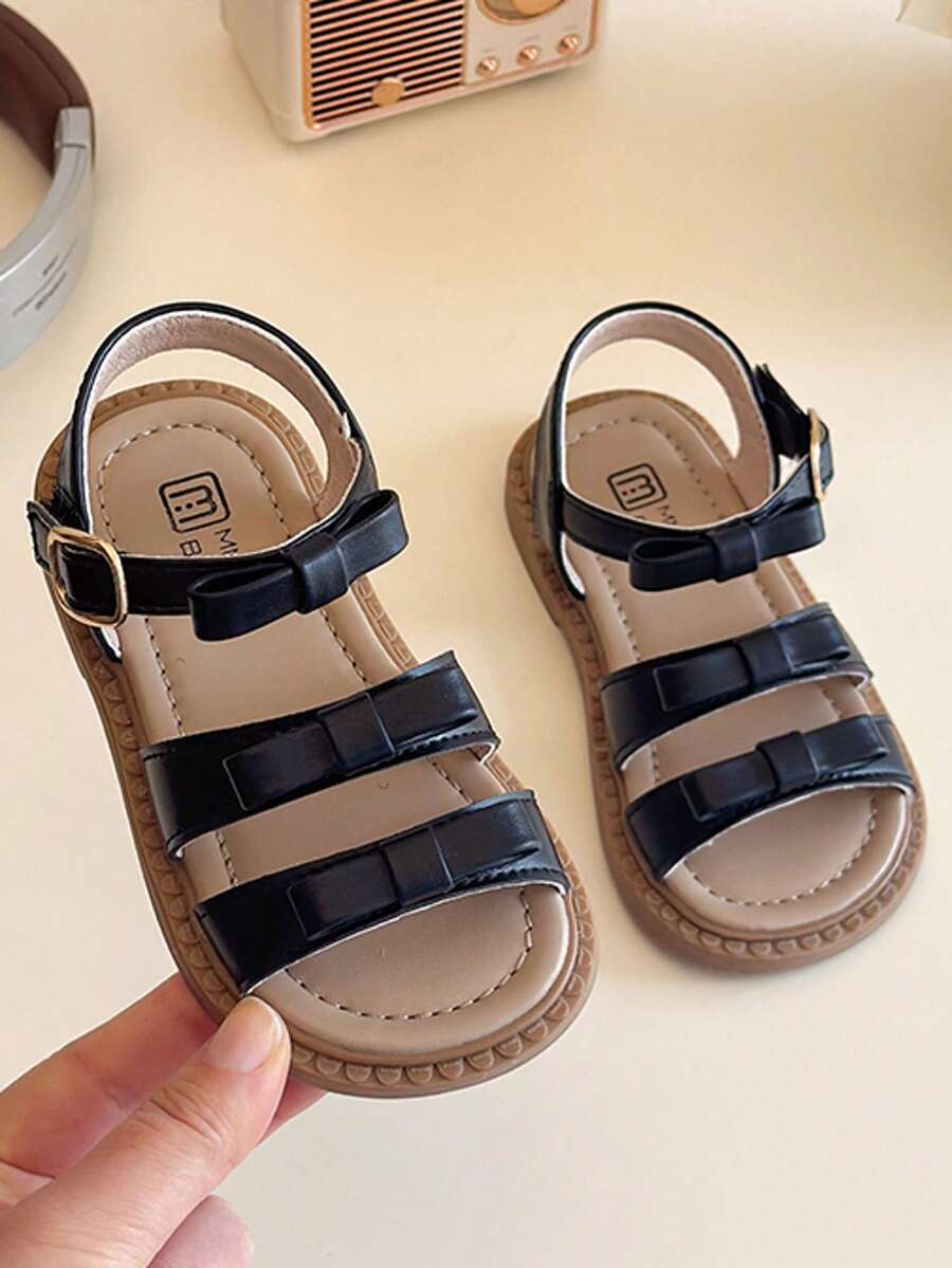 A Pair Of Popular Sandals With Multiple Straps And Bow Trim, A Metal Buckle Design And A Brown Sole. The Style Is Simple And Fashionable, Belongs To The Summer Popular Style, Suitable For Children's Daily Activities, Vacation And Other Scenes, Suitable For 3-12 Years Old Children To Wear - Black - View 1