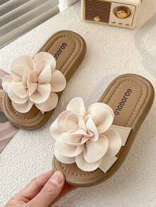 一双夏季热销儿童防滑拖鞋。鞋面饰有大朵浅米色花朵，造型逼真，立体感十足。鞋底为浅棕色，鞋垫印有“GOJO”字样。整体风格甜美可爱，适合3-12岁女童居家、散步等休闲场合穿着，更能增添童真童趣。