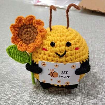 1/3件趣味手工钩针蜜蜂娃娃挂饰，是馈赠亲朋好友和爱人的理想礼物。充满正能量的娃娃手中拿着写有鼓励话语的卡片，还有一朵向日葵。