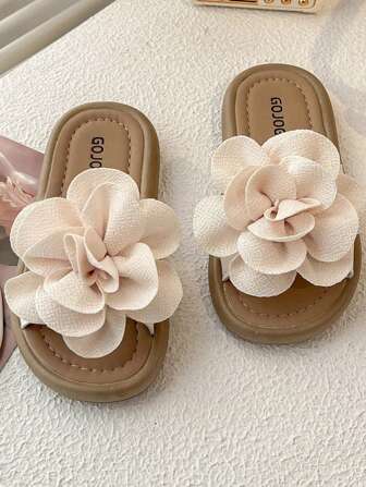 Un par de chanclas de verano antideslizantes para niños. La parte superior del calzado está decorada con grandes flores beige claro de forma realista y con un gran sentido tridimensional. La suela es de color marrón claro y la plantilla está impresa con la palabra "GOJO". El estilo general es dulce y encantador, adecuado para que las niñas de 3 a 12 años lo usen en casa, para caminar y en otros eventos casuales, y puede agregar un toque de inocencia y diversión.