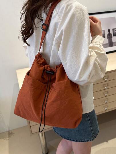 Esta bolsa de hombro con forma de cubo minimalista cuenta con una correa de hombro ajustable y un cierre de cordón. Hecha de un material de nailon especial, es ligera y transpirable. El diseño de unicolor es adecuado para salidas diarias y viajes al trabajo tanto para hombres como para mujeres.