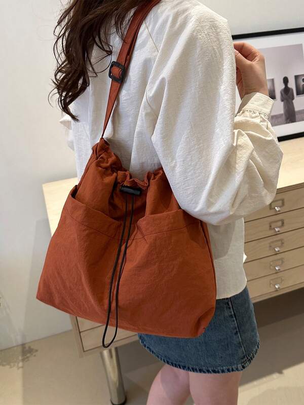 这款简约水桶形斜挎包配有可调节肩带和抽绳封口。采用特殊尼龙材质，轻盈透气。纯色设计，男女皆宜，适合日常出行和通勤。