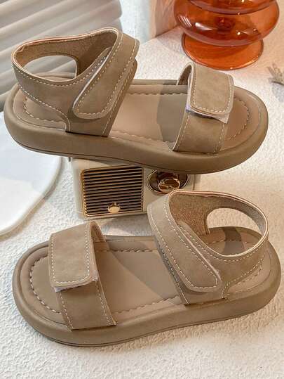 一双夏季畅销儿童防滑凉鞋。鞋面为卡其色，采用双钩环绑带设计，方便穿脱和调节松紧度。整体风格简约休闲，适合3-12岁儿童日常外出和玩耍穿着，舒适实用。