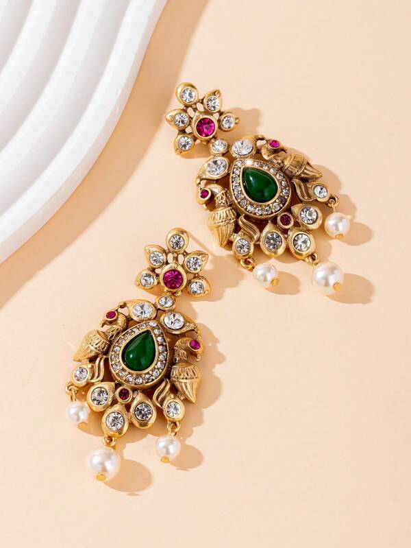 This Is A Pair Of Earrings With A Strong Bohemian Style. The Base Is In Gold Color, Inlaid With Green Teardrop-Shaped Gemstones, Red Gemstones, White Diamonds, And Pearls. The Green Gemstones Could Be Jade Or Synthetic Emerald, Symbolizing Vitality And Energy; The Red Gemstones Like Rubies Represent Passion; The Diamonds Sparkle And Shine, Representing Eternity.