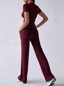 Tuta sportiva da donna alla moda per la primavera, con top a maniche corte che scopre la pancia e pantaloni a zampa aderenti con lacci