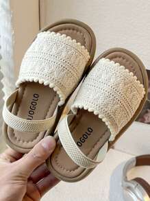 A Pair Of Children's Sandals. The Upper Is Made Of Cream-Colored Crochet Material, And The Edge Is Decorated With Pompoms. The Design Is Exquisite And Cute, And The Hook And Loop Belt Of The Same Color Is Matched. The Overall Style Is Sweet And Casual, Suitable For 3-12 Year Old Girls In The Summer Daily Travel, Walking And Other Occasions To Wear, Can Show The Pure And Lovely Elegant.