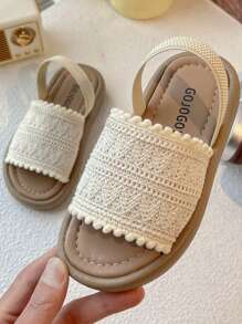 A Pair Of Children's Sandals. The Upper Is Made Of Cream-Colored Crochet Material, And The Edge Is Decorated With Pompoms. The Design Is Exquisite And Cute, And The Hook And Loop Belt Of The Same Color Is Matched. The Overall Style Is Sweet And Casual, Suitable For 3-12 Year Old Girls In The Summer Daily Travel, Walking And Other Occasions To Wear, Can Show The Pure And Lovely Elegant.