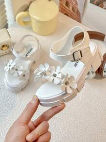 Un par de sandalias de plataforma blancas de moda de verano para niñas de 3 a 12 años, con elementos decorativos florales para un toque romántico. La parte superior es suave y cómoda, con diseño de gancho y lazo para un ajuste fácil, ya sea para juegos en interiores o paseos al aire libre, puede proporcionar un acompañamiento cómodo para los niños.