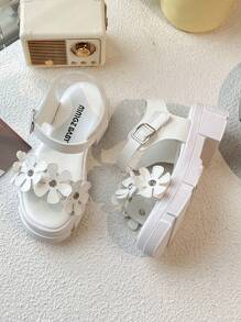 Un par de sandalias de plataforma blancas de moda de verano para niñas de 3 a 12 años, con elementos decorativos florales para un toque romántico. La parte superior es suave y cómoda, con diseño de gancho y lazo para un ajuste fácil, ya sea para juegos en interiores o paseos al aire libre, puede proporcionar un acompañamiento cómodo para los niños.