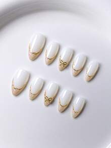 10片手工法式短指甲贴纸。这款美甲套装包含5种颜色：白色、粉色、金色、蓝色和黄色，设计迷人可爱。每张指甲贴纸都饰有手绘藤蔓图案，沿着金属法式边缘蜿蜒而下，并点缀着金色和钻石蝴蝶结。 - 白色 - 查看 3