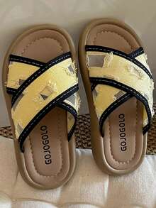 A Pair Of Children's/Girls' Slippers. The Upper Of The Shoe Features A Yellow Fabric With A Black Webbed Interlaced Design. The Yellow Part Has An Aged And Perforated Effect. The Sole Is Light Brown. The Overall Style Is Casual And Fashionable, With A Feel. It Is Suitable For Girls Aged 3 To 12 To Wear At Home Or For Short Outdoor Activities In Summer, And Can Show A Lively And Playful Elegant.