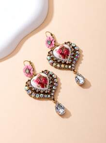 Il s'agit d'une paire de boucles d'oreilles bien conçues. Le style appartient à l'esthétique vintage et romantique, en mélangeant divers éléments : - Conception principale : Pièces en céramique en forme de cœur avec des motifs floraux rouges, ce qui donne une ambiance artistique et romantique. - Éléments décoratifs : les bords des formes de cœur sont garnis de nombreux strass scintillants, ajoutant une touche de luxe.