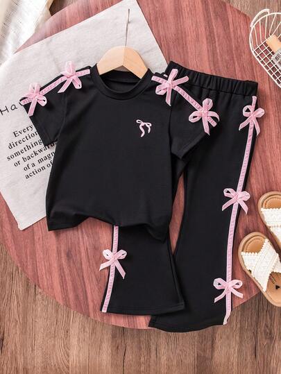 مجموعة ملابس علوية أكمام قصيرة سوداء وبنطلون واسع للبنات. البلوزة تميزها زينة وردية على الكتف بشكل فراشة رقيق وبسيط لكن ديناميكي. البنطلون الواسع مزين بأقواس بألوان مطابقة على الجوانب، أنيق وملفت للنظر. مناسب للخروجات اليومية، التجمعات مع الأصدقاء، يخلق إطلالة عذبة وجذابة بسهولة.