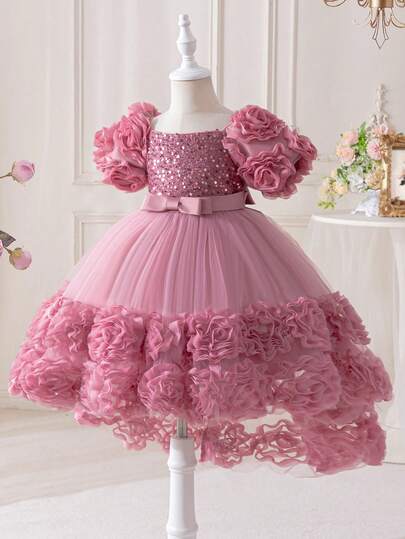 Một chiếc váy sequin màu hồng có đuôi dành cho bé gái, có trang trí nơ ở eo và hoa 3D ở viền và tay áo. Thích hợp cho những dịp quan trọng như tiệc sinh nhật, tiếp khách, biểu diễn sân khấu, cuộc thi piano và nhiều lễ hội quan trọng khác. Chiếc váy rất sáng bóng và rực rỡ khi mặc.