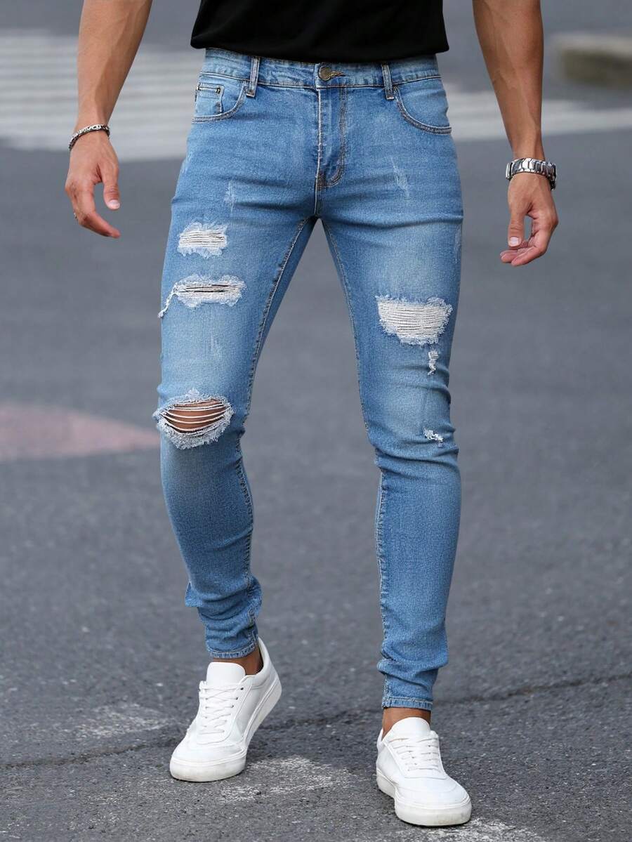 Pantalones jeans ajustados para hombres en denim azul claro con efecto de desgaste y rotura, tela suave y elástica, ideales para estilos casuales y modernos - Azul lavado medio - Ver 1