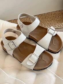 A Pair Of Children's /2025 New Girls' Sandals, With A Beige Matte Upper, Featuring A Double Strap And Metal Buckle Design, And A Wraparound Strap At The Ankle, Presenting A Simple And Fashionable Style.