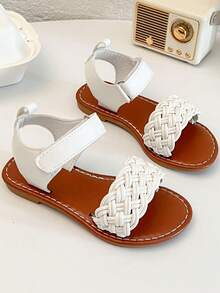 一双畅销儿童/女童凉鞋。鞋面采用白色皮革制成。前脚掌处有精致的编织图案，脚踝处有绑带。