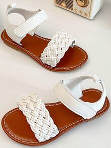 一双畅销儿童/女童凉鞋。鞋面采用白色皮革制成。前脚掌处有精致的编织图案，脚踝处有绑带。