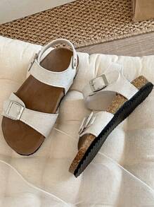 A Pair Of Children's /2025 New Girls' Sandals, With A Beige Matte Upper, Featuring A Double Strap And Metal Buckle Design, And A Wraparound Strap At The Ankle, Presenting A Simple And Fashionable Style.