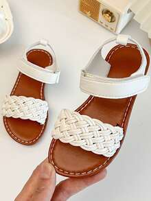 一双畅销儿童/女童凉鞋。鞋面采用白色皮革制成。前脚掌处有精致的编织图案，脚踝处有绑带。