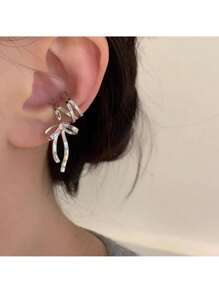 Elegant Silver Tone Ribbon Bow Ear Cuff With Sparkling Gem Accent: Chic Non-Piercing Ear Wrap Featuring A Delicate Layered Ribbon Bow Design With A Subtle Sparkling Gemstone Accent, Comfortable And Adjustable Clip-On Style For Non-Pierced Ears, Adds A Touch Of Feminine Charm And Whimsical Elegance To Any Outfit, Perfect For Everyday Wear, Parties, Weddings, Special Occasions, And Expressing Individual Style, Lightweight And Easy To Wear, Makes A Wonderful Gift For Women And Teen Girls Who Love Unique And Non-Pierced Jewelry, Versatile Design Can Be Worn Alone Or Paired With Other Earrings For A Layered Look.