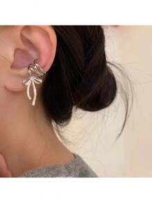 Elegant Silver Tone Ribbon Bow Ear Cuff With Sparkling Gem Accent: Chic Non-Piercing Ear Wrap Featuring A Delicate Layered Ribbon Bow Design With A Subtle Sparkling Gemstone Accent, Comfortable And Adjustable Clip-On Style For Non-Pierced Ears, Adds A Touch Of Feminine Charm And Whimsical Elegance To Any Outfit, Perfect For Everyday Wear, Parties, Weddings, Special Occasions, And Expressing Individual Style, Lightweight And Easy To Wear, Makes A Wonderful Gift For Women And Teen Girls Who Love Unique And Non-Pierced Jewelry, Versatile Design Can Be Worn Alone Or Paired With Other Earrings For A Layered Look.