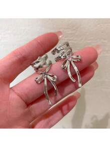 Elegant Silver Tone Ribbon Bow Ear Cuff With Sparkling Gem Accent: Chic Non-Piercing Ear Wrap Featuring A Delicate Layered Ribbon Bow Design With A Subtle Sparkling Gemstone Accent, Comfortable And Adjustable Clip-On Style For Non-Pierced Ears, Adds A Touch Of Feminine Charm And Whimsical Elegance To Any Outfit, Perfect For Everyday Wear, Parties, Weddings, Special Occasions, And Expressing Individual Style, Lightweight And Easy To Wear, Makes A Wonderful Gift For Women And Teen Girls Who Love Unique And Non-Pierced Jewelry, Versatile Design Can Be Worn Alone Or Paired With Other Earrings For A Layered Look.