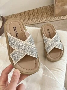 Un par de chanclas para niñas de talla grande vendidas/nuevas 2025 con un diseño de tira cruzada en la parte superior y adornadas con una gran cantidad de brillantes rhinestones, presentando un estilo lujoso y de moda. La suela está impresa con el logotipo de la marca. El diseño general es adecuado para que las niñas de 3 a 12 años las usen en salidas diarias, asistir a fiestas y otros eventos. Son unas chanclas para niñas con estilo y brillo, que combinan belleza y comodidad.