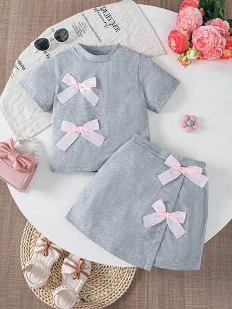 Conjunto de moda de verano para niñas con decoración de lazo, blusa de cuello redondo de manga corta + falda con bajo asimétrico, conjunto casual de camiseta apta para niñas de 4 a 7 años, para uso diario, al aire libre, calle, campus y fiestas