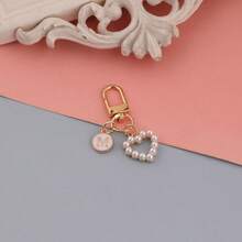 Um pingente de bolsa com pingente circular rosa com letras de A a Z, com um chaveiro de pérola em formato de coração e um estilo elegante e simples. É perfeito para combinar com fantasias de Halloween e para estudantes universitários e do ensino fundamental. Também é um pingente de bolsa, chaveiro de carro, para aniversários, feriados, volta às aulas, ideal para presentear familiares, amigos, namorados, presentes de aniversário, presentes de feriado, presentes de Dia das Mães, presentes de Dia dos Professores.