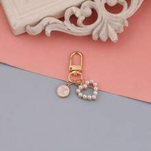 Um pingente de bolsa com pingente circular rosa com letras de A a Z, com um chaveiro de pérola em formato de coração e um estilo elegante e simples. É perfeito para combinar com fantasias de Halloween e para estudantes universitários e do ensino fundamental. Também é um pingente de bolsa, chaveiro de carro, para aniversários, feriados, volta às aulas, ideal para presentear familiares, amigos, namorados, presentes de aniversário, presentes de feriado, presentes de Dia das Mães, presentes de Dia dos Professores.