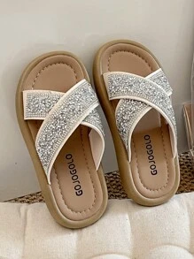 Un par de chanclas para niñas de talla grande vendidas/nuevas 2025 con un diseño de tira cruzada en la parte superior y adornadas con una gran cantidad de brillantes rhinestones, presentando un estilo lujoso y de moda. La suela está impresa con el logotipo de la marca. El diseño general es adecuado para que las niñas de 3 a 12 años las usen en salidas diarias, asistir a fiestas y otros eventos. Son unas chanclas para niñas con estilo y brillo, que combinan belleza y comodidad.