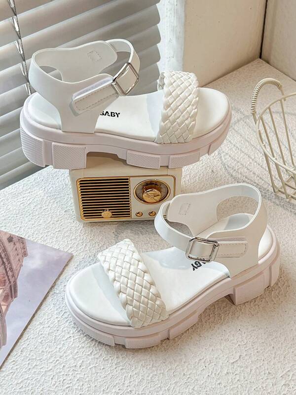 Un par de sandalias para niños/niñas. El Body principal de la Top es blanco. Las correas entretejidas están en una combinación de azul y rosa. Hay una correa con hebilla de metal en el tobillo.