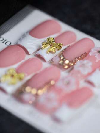 10 件可爱甜美的白色和粉色方形按压指甲，手工制作的金色蝴蝶结假指甲，粉红色为主色调，搭配白色法式边缘，闪亮的金色蝴蝶结增添奢华感，精致的珍珠和水钻链条彰显优雅，立体花朵造型俏皮灵动，适合日常生活、约会、派对、节日等场合，是送给女士和女孩的绝佳礼物