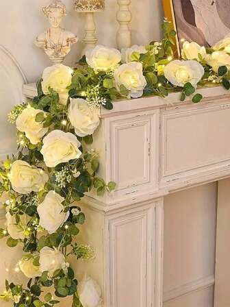 人造桉树藤蔓搭配白玫瑰花环，白色花朵和绿叶，配以童话般的彩灯，适合婚礼餐桌中心装饰、过道装饰、背景墙装饰，适用于婚宴、新娘送礼会、主题派对