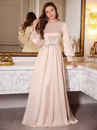 Vestido largo de satén con mangas largas y corte evasé con cintura anudada, que estiliza y levanta la figura de la mujer