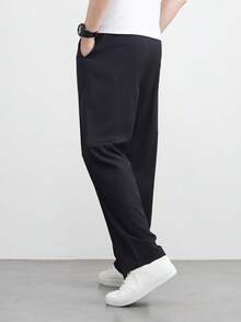 زوج من البناطيل السوداء الرجالية الفضفاضة ذات الساق المستقيمة والواسعة، كاجوال ومتعددة الاستخدامات، قابلة للغسل بالغسالة، بتصميم خصر ربطة