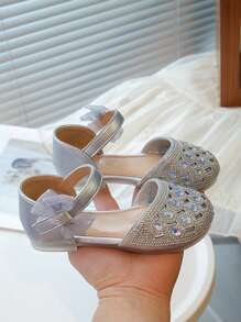 Un par de zapatos planos para niñas de estilo princesa dulce con decoraciones de lazo con diamantes de agua y hebillas para uso en fiestas y días festivos