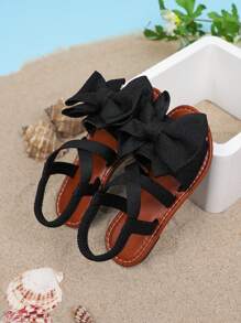 1 par de sandalias planas de unicolor para niñas, con diseño de tiras cruzadas con decoración de moño, y suela suave y cómoda, adecuada para salidas de verano, viajes a la playa y vacaciones de las niñas