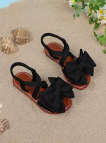 1 par de sandalias planas de unicolor para niñas, con diseño de tiras cruzadas con decoración de moño, y suela suave y cómoda, adecuada para salidas de verano, viajes a la playa y vacaciones de las niñas