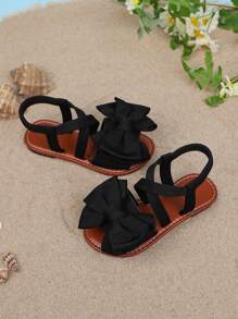 1 par de sandalias planas de unicolor para niñas, con diseño de tiras cruzadas con decoración de moño, y suela suave y cómoda, adecuada para salidas de verano, viajes a la playa y vacaciones de las niñas