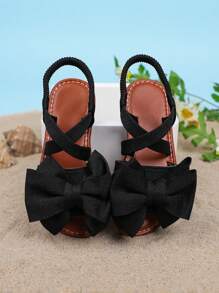 1 par de sandalias planas de unicolor para niñas, con diseño de tiras cruzadas con decoración de moño, y suela suave y cómoda, adecuada para salidas de verano, viajes a la playa y vacaciones de las niñas
