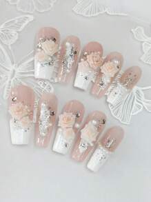 Un ensemble de 10 manucures en forme de cercueil longues et délicatement conçues, avec des pointes françaises blanches peintes à la main style Y2K, des feuilles d'argent et d'or brillantes, ainsi qu'un design 3D haut de gamme avec fleurs de camélia, strass et chaîne de perles de fantaisie.