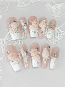 Un ensemble de 10 manucures en forme de cercueil longues et délicatement conçues, avec des pointes françaises blanches peintes à la main style Y2K, des feuilles d'argent et d'or brillantes, ainsi qu'un design 3D haut de gamme avec fleurs de camélia, strass et chaîne de perles de fantaisie.