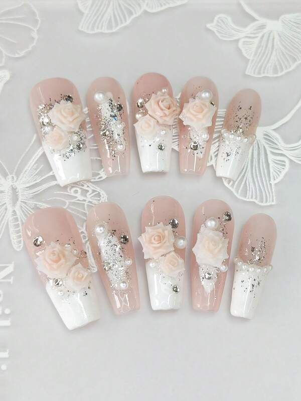 Un ensemble de 10 manucures en forme de cercueil longues et délicatement conçues, avec des pointes françaises blanches peintes à la main style Y2K, des feuilles d'argent et d'or brillantes, ainsi qu'un design 3D haut de gamme avec fleurs de camélia, strass et chaîne de perles de fantaisie.