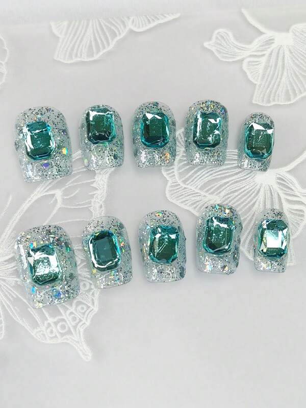 1 ensemble de 10 pièces d'ongles carrés courts et exquis avec de fins paillettes irisées peintes à la main et des pierres précieuses bleu saphir glacé. Cet accessoire d'ongles faux de style minimaliste allonge la longueur des doigts et ajoute une touche de mode à vos ongles.